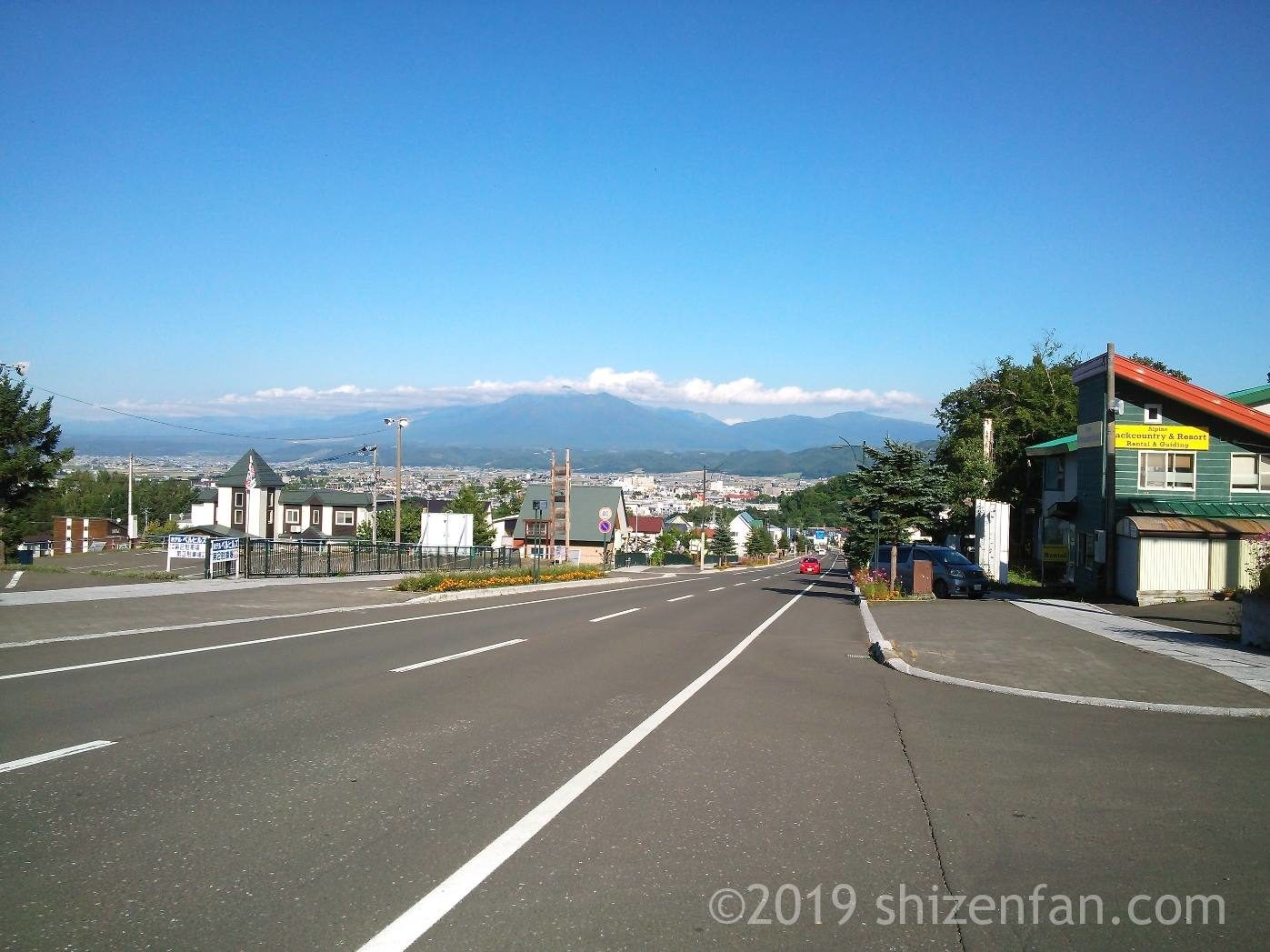 富良野スキー場北の峰ベース側から見下ろす道路と街並み、山々