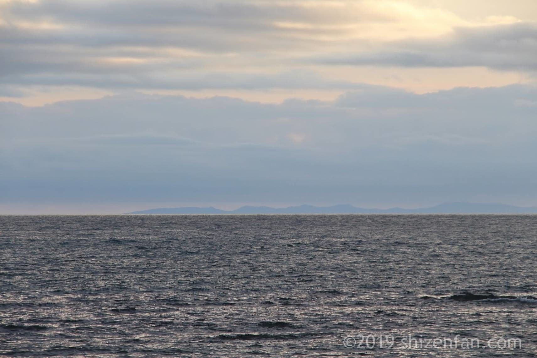 夕暮れの稚内のノシャップ岬、海の向こうに見える島の陰