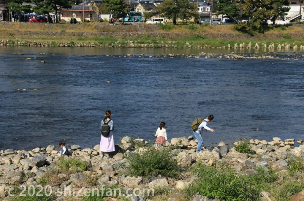 京都・嵐山の川辺の風景（石投げをする家族